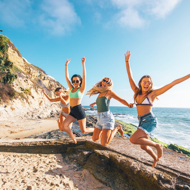 Four girls jumping near the ocean